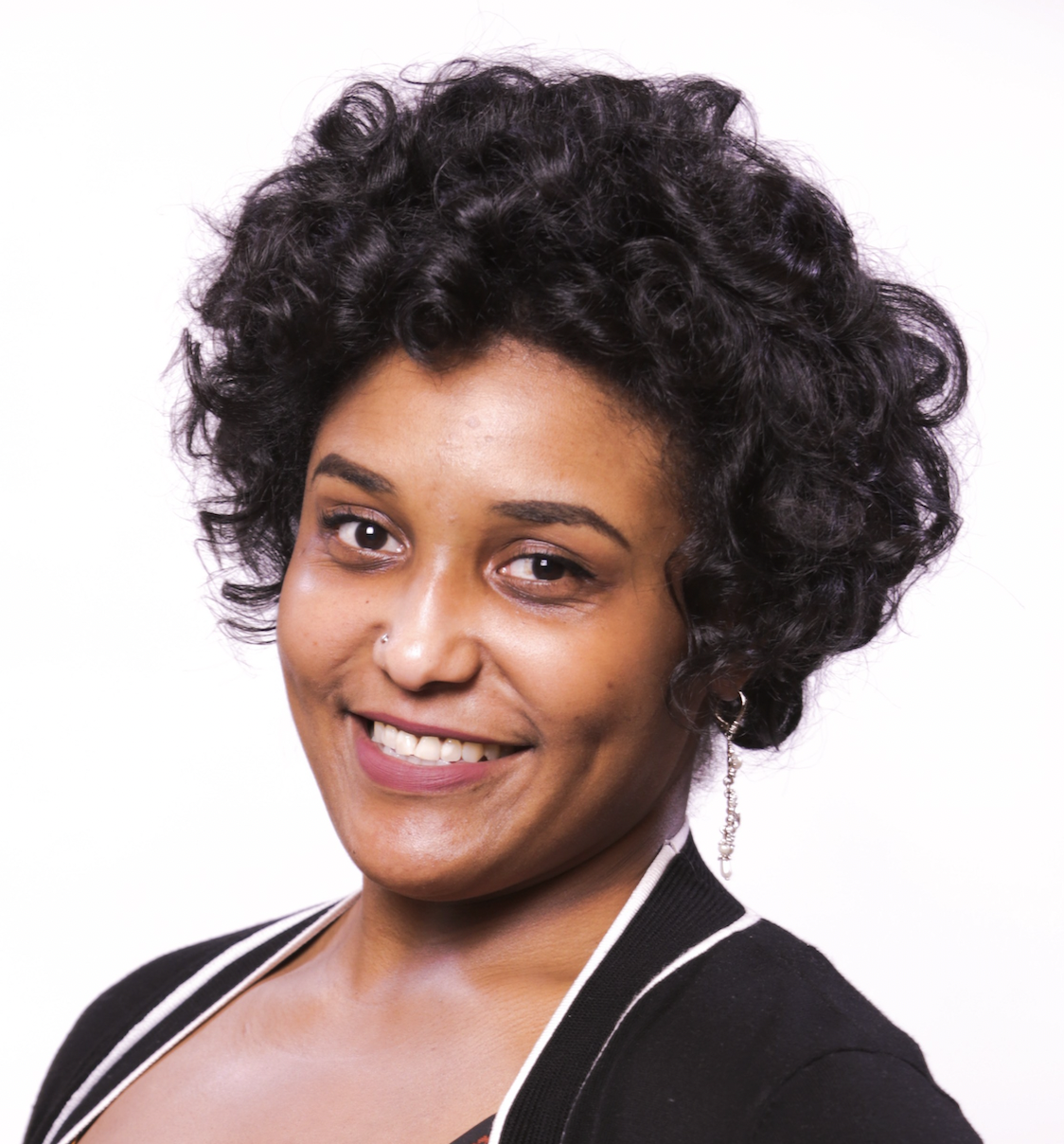 Whitney is an African American female with short black curly hair, smiling in front of a white background and wearing a black sweater with a black and gold decorated top.