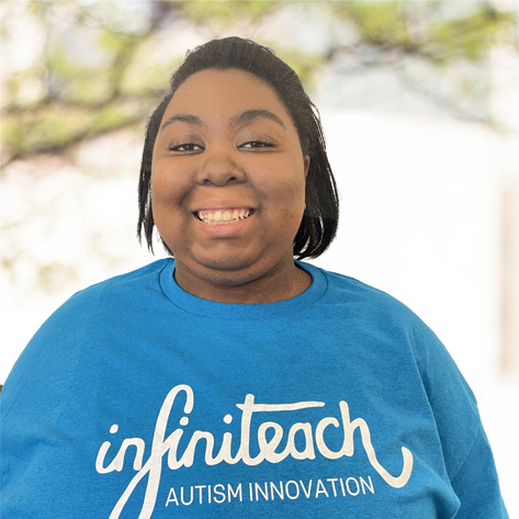 Aliyah is an African-American woman with short black hair who is wearing a blue shirt that says Infiniteach Autism Innovation.