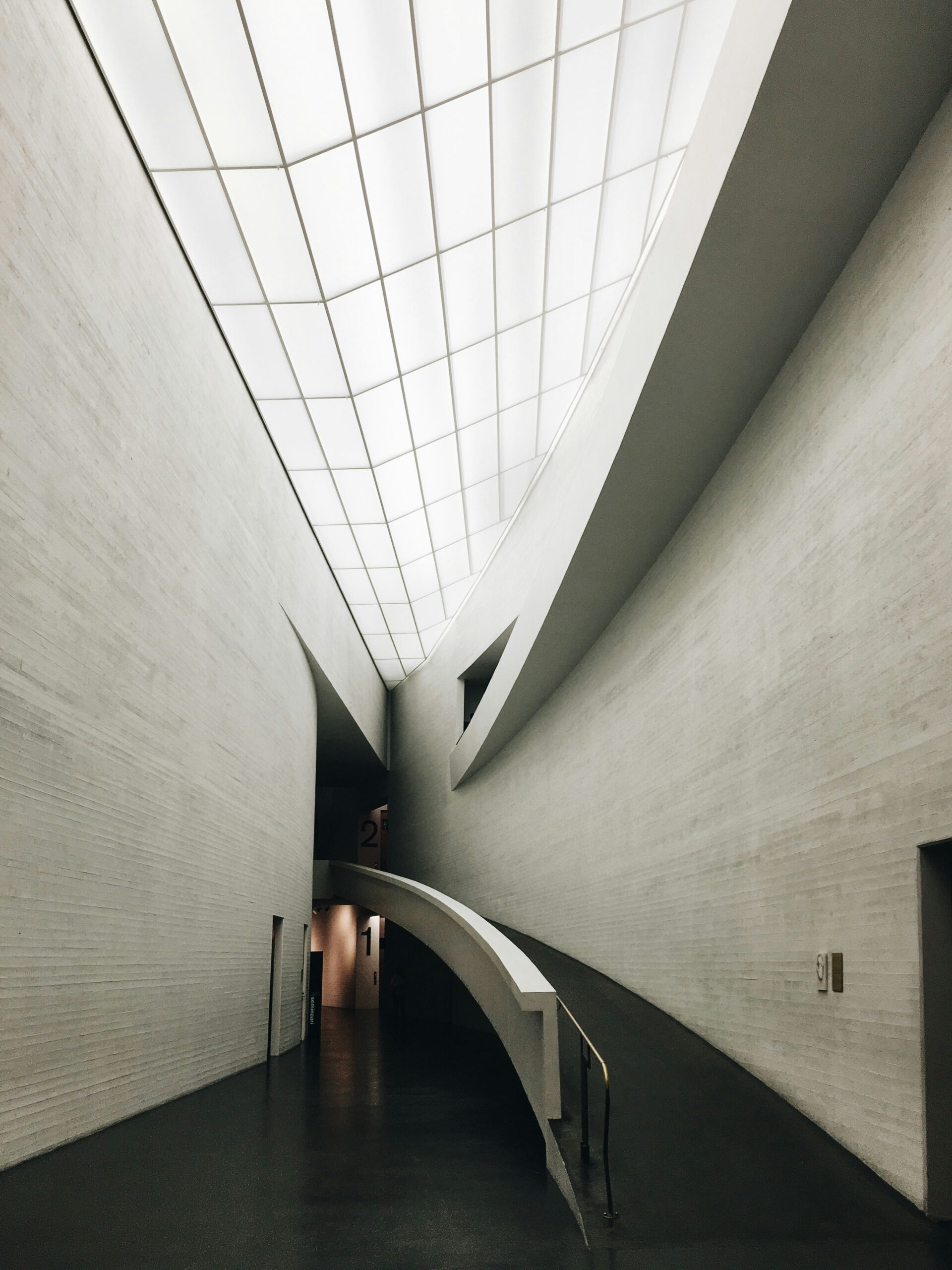Modern interior of a white building with long ramp leading to higher level. Photo by Stefan Spassov on Unsplash.
