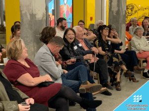 Fundraiser guests seated in a brightly colored room laughing.