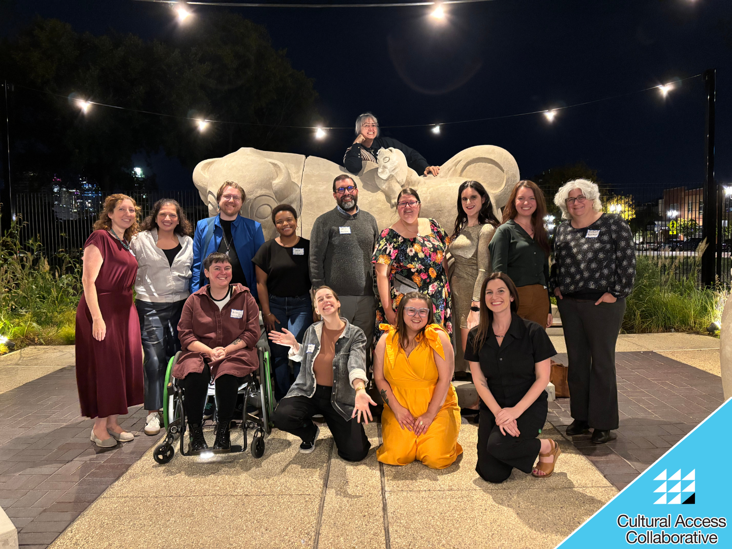 Current and former members of the Steering Committee and Board smile in front of a large bull statue in the courtyard. Co-Chair Zhen is popping up from behind the statue.