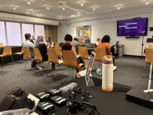 Photo of guests seated in rows viewing screen with captions.