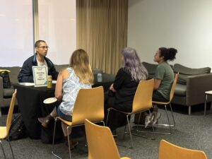 Photo of guests chatting with presenter Jaden Dueñas at a table.