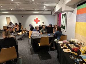 Photo of guests chatting at a table near the snacks table at the LEAD 2026 Share Out