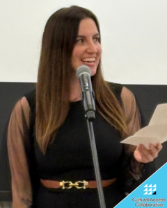 Christena stands in front of a mic smiling off to the side.