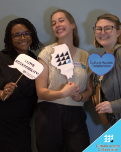 SC Members Daria, Mikaela, and Lauren pose in the photo booth with CAC logo props smiling.
